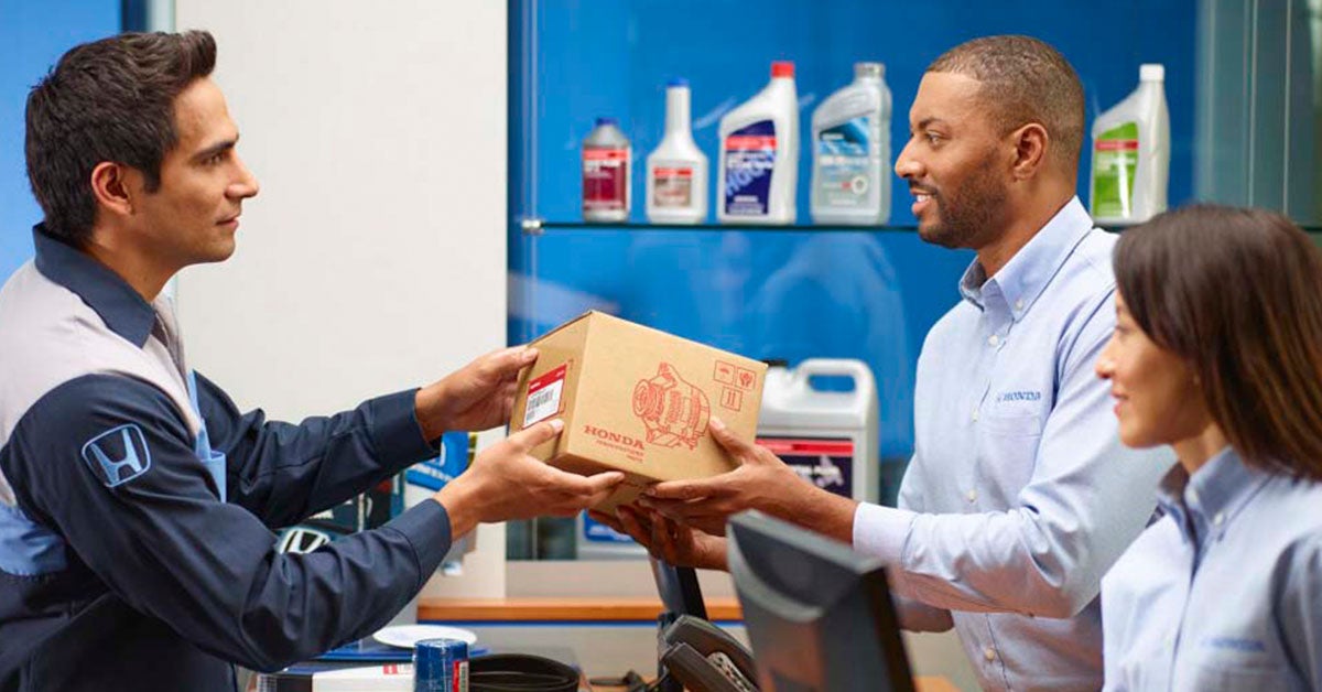 Technician handing parts to customer at a Honda service center