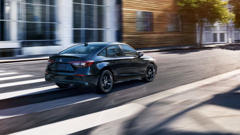 2026 Honda Civic Sedan Sport Hybrid speeding down a street highlighting fuel efficiency design features and aerodynamics